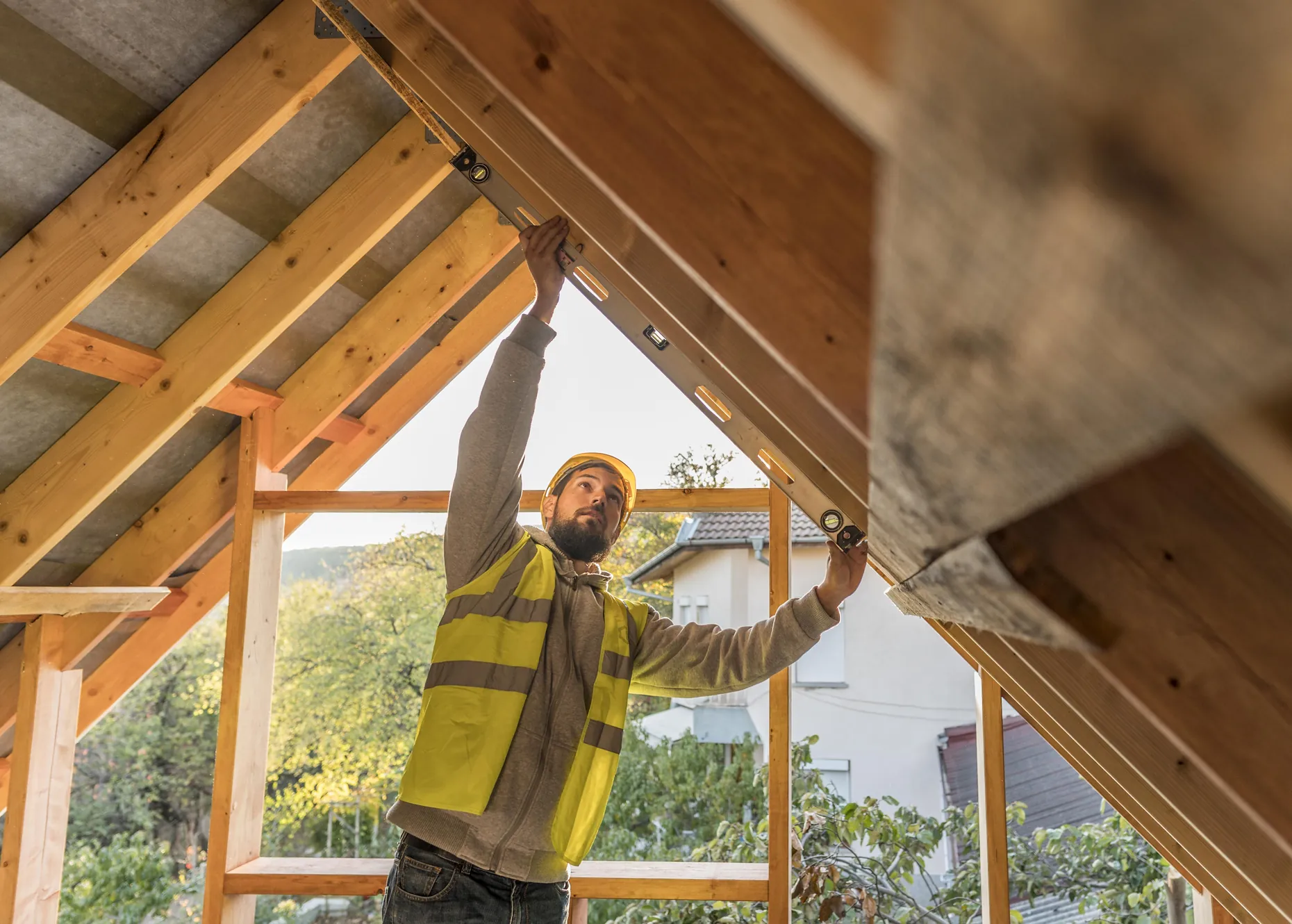 Charpentier couvreur mesurant une charpente bois sous toiture